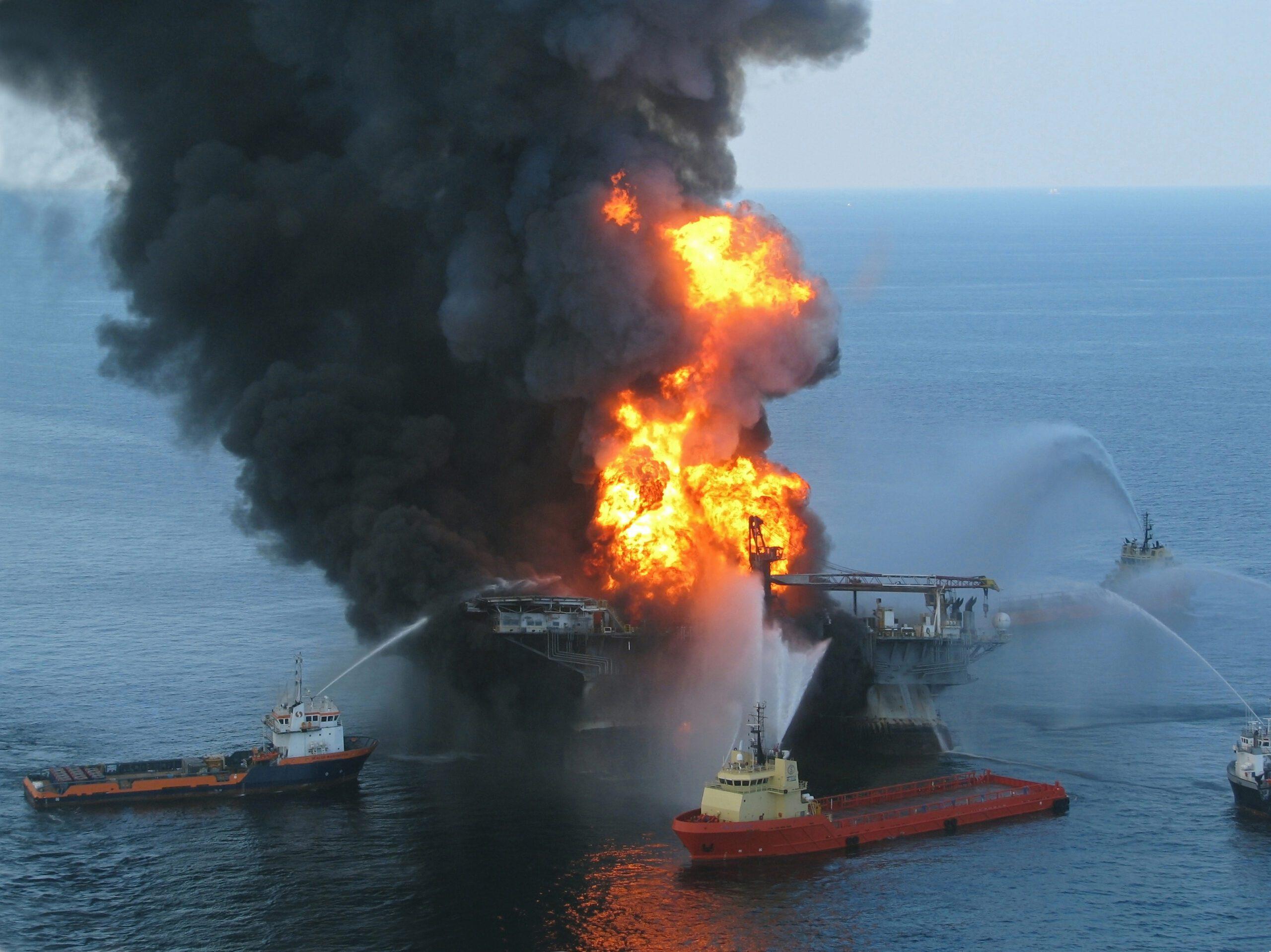 An oil rig engulfed in flames, with thick smoke billowing into the sky
