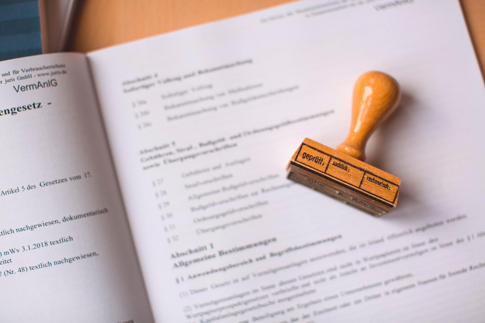 A rubber stamp resting on an open book, with a stamped paper placed beside it