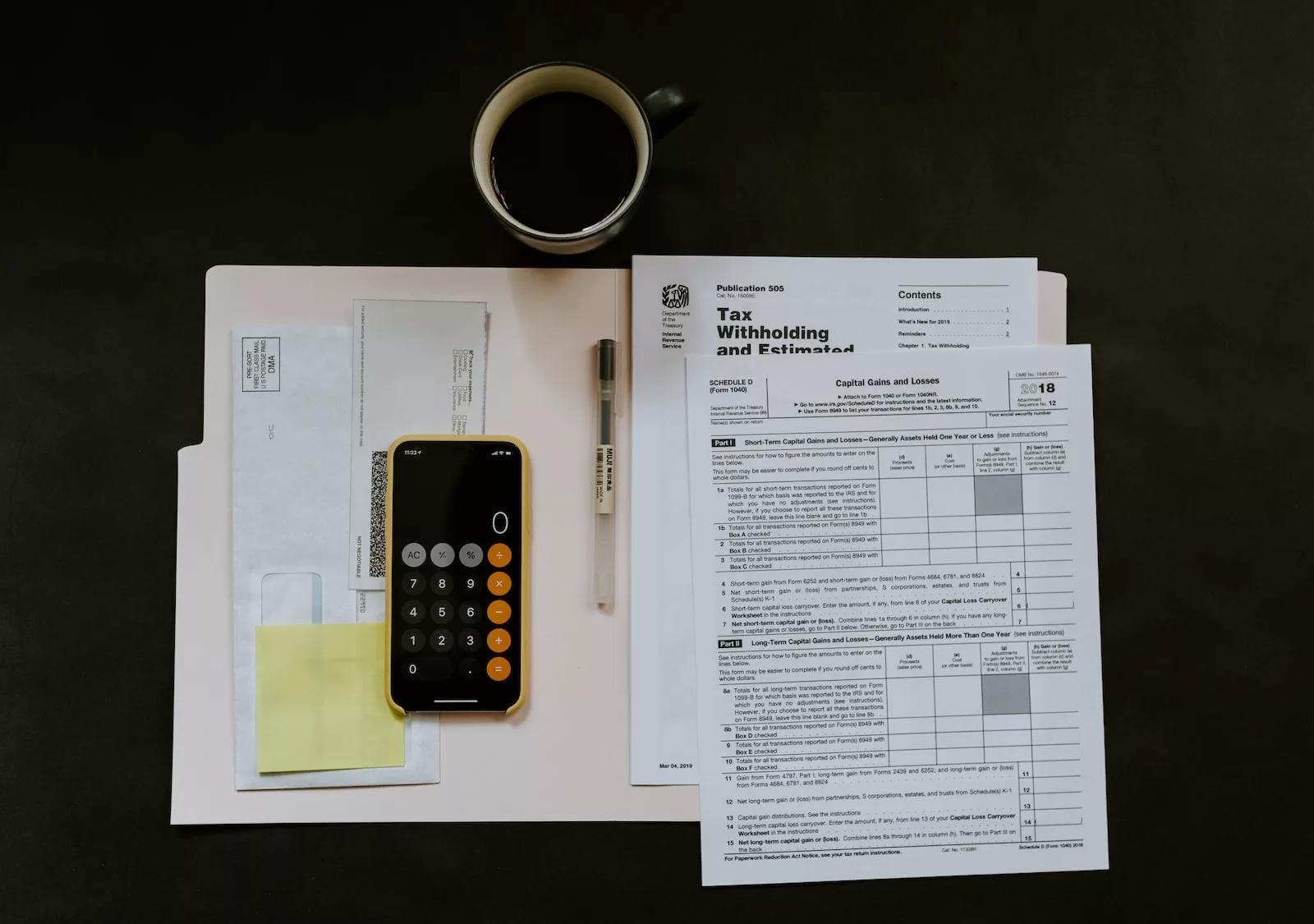 Tax forms and a calculator arranged on a wooden desk